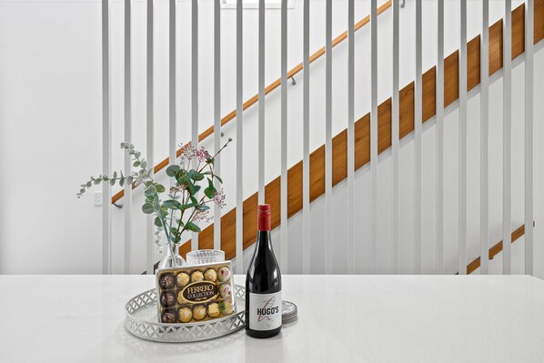 Uma mesa com uma caixa de Ferrero Collection, uma garrafa de vinho Hugos e um vaso com flores.