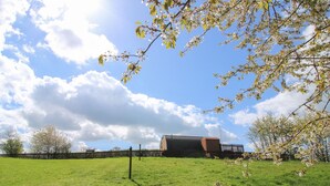 A grassy field with a building in the background. - Cherry Pod 2 (Shrewsbury)