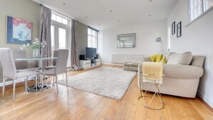 Uma sala de estar moderna com sofá, poltronas, mesa de vidro e televisão.