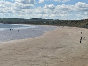 Ein weiter Sandstrand mit sanften Wellen und blauem Himmel.