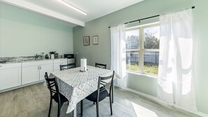 A modern kitchen with a dining table, chairs, and a window with curtains. - Peaceful Harvest Home in Hutto (hutto)