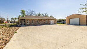 A two-story building with a stone facade and a large garage door. - Peaceful Harvest Home in Hutto (hutto)