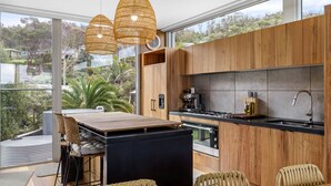 A modern kitchen with wooden cabinets, a black countertop, and a large window overlooking a garden. - Six Degrees - Across the road from the Separation Creek beach (Separation Creek)