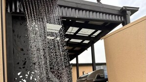 Una fuente de agua con efecto cascada, una parrilla y un patio cubierto.