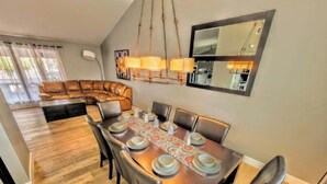 A dining area with a wooden table set for six, surrounded by leather chairs. A large mirror hangs on the wall above the table. - Oasis w/Opt Heated Pool & Billiards- Mins to Strip (Las Vegas)