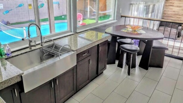 A kitchen with a large window, a sink, and a dining area with stools. - Oasis w/Opt Heated Pool & Billiards- Mins to Strip (Las Vegas)