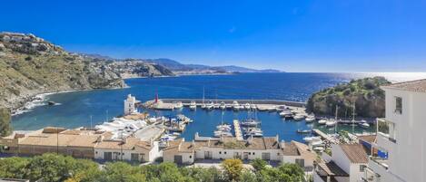 Un pueblo costero con un puerto deportivo, edificios blancos y un mar azul cristalino.