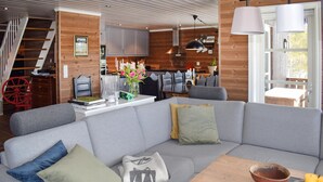 Una sala moderna con un sofá seccional gris, una mesa de centro de madera y una cocina al fondo.