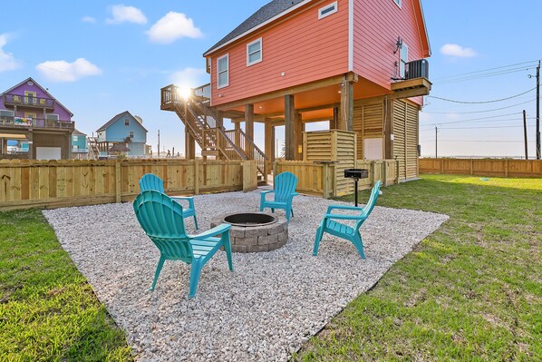 A backyard with a fire pit, turquoise chairs, and a wooden deck. - Ocean & Bay Views, Steps To The Beach, EV Charging, LG Fenced Yard, Fire Pit (Surfside Beach)