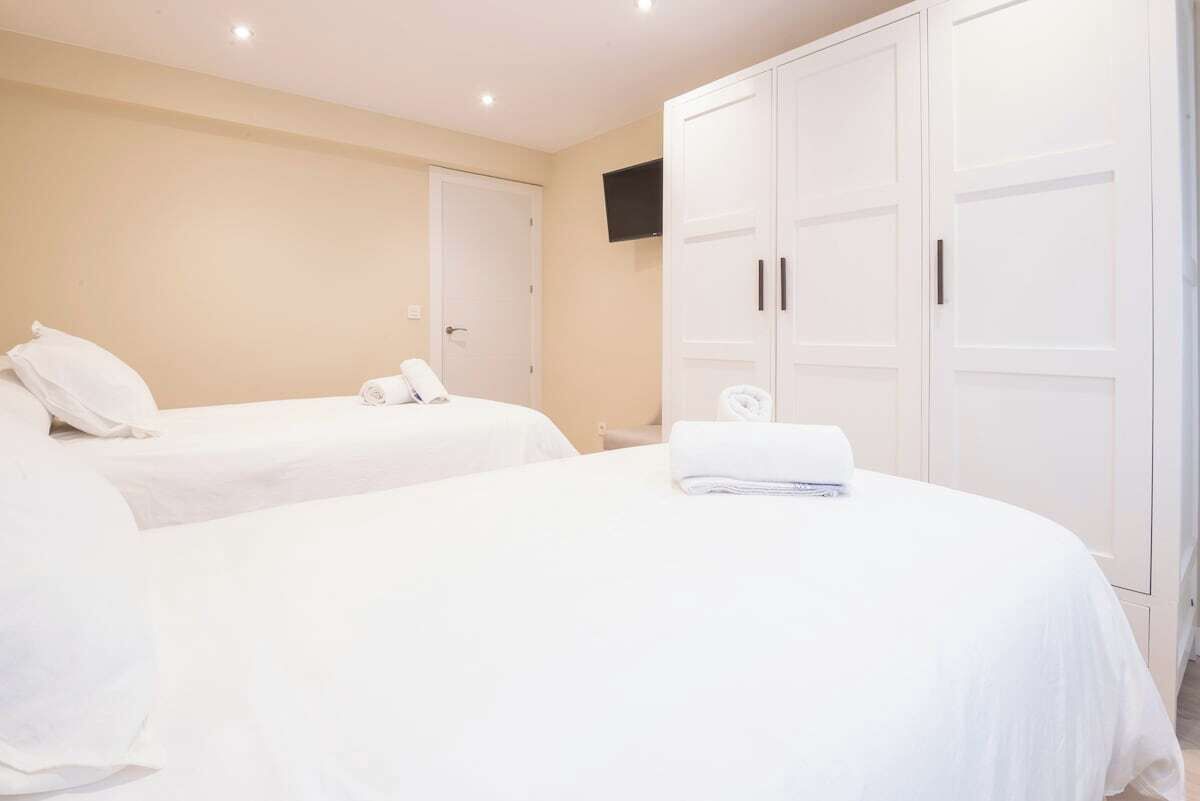 Une chambre d’hôtel avec deux lits, une armoire, un téléviseur et une porte.