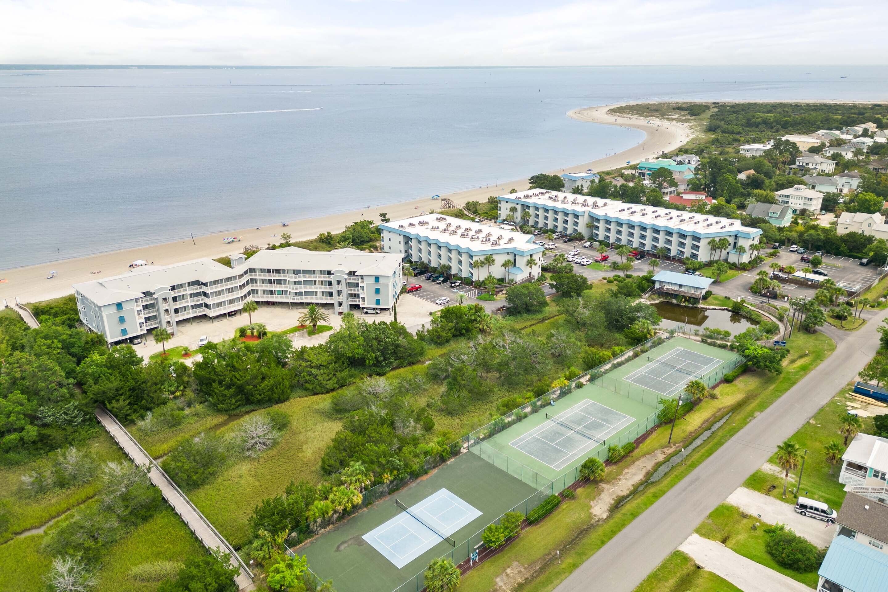 Et kysthotel med flere bygninger, en strand og tennisbaner.