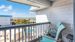 A balcony with a view of a pool and a building across the water. - Beach Racquet A313 by Tybee Vacation Rentals (Tybee Island)