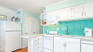 A kitchen with white cabinets, a stove, and a sink. - Beach Racquet A313 by Tybee Vacation Rentals (Tybee Island)