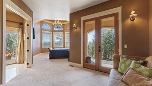 A spacious room with a large bed, a sofa, and a balcony with a view of greenery. - Beautiful Country Villa on 5 acres, 5 miles to downtown (Spokane)