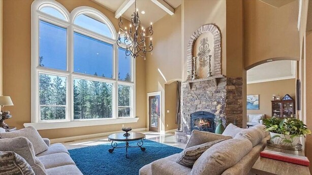 A spacious living room with a fireplace, large windows, and a chandelier. - Beautiful Country Villa on 5 acres, 5 miles to downtown (Spokane)