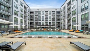 A modern hotel with a central swimming pool, sun loungers, and outdoor seating areas. - Art house sawyer yards (Houston)