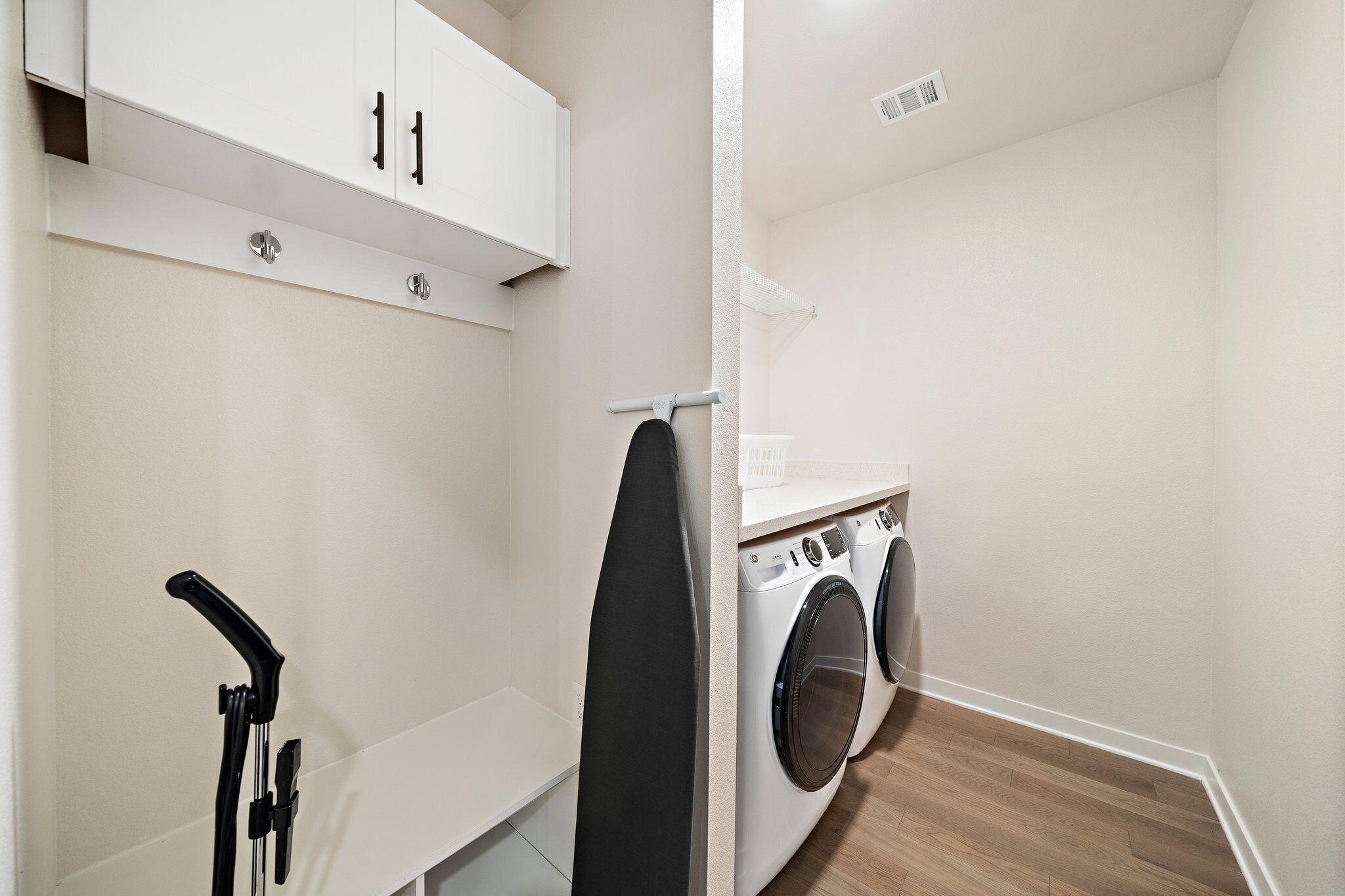 A laundry room with a washing machine, dryer, and ironing board.