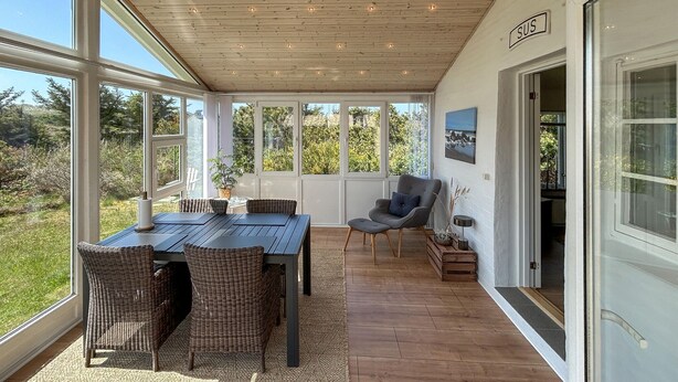A covered patio with a table and chairs, large windows, and a door labeled 'SUS'. - 2 bedroom gorgeous home in Ulfborg (Ulfborg)