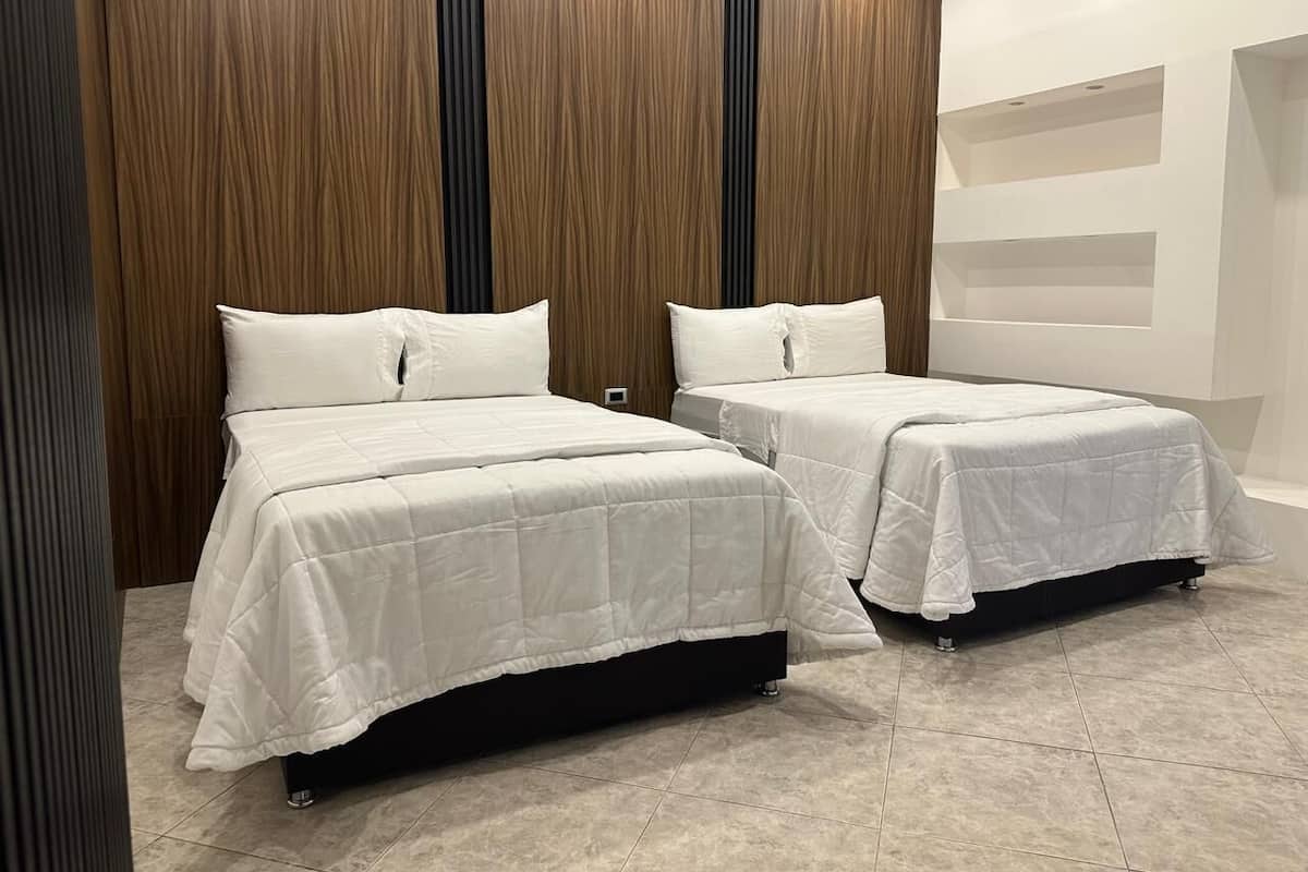 Two single beds with white bedding in a modern room with wooden paneling and a tiled floor.