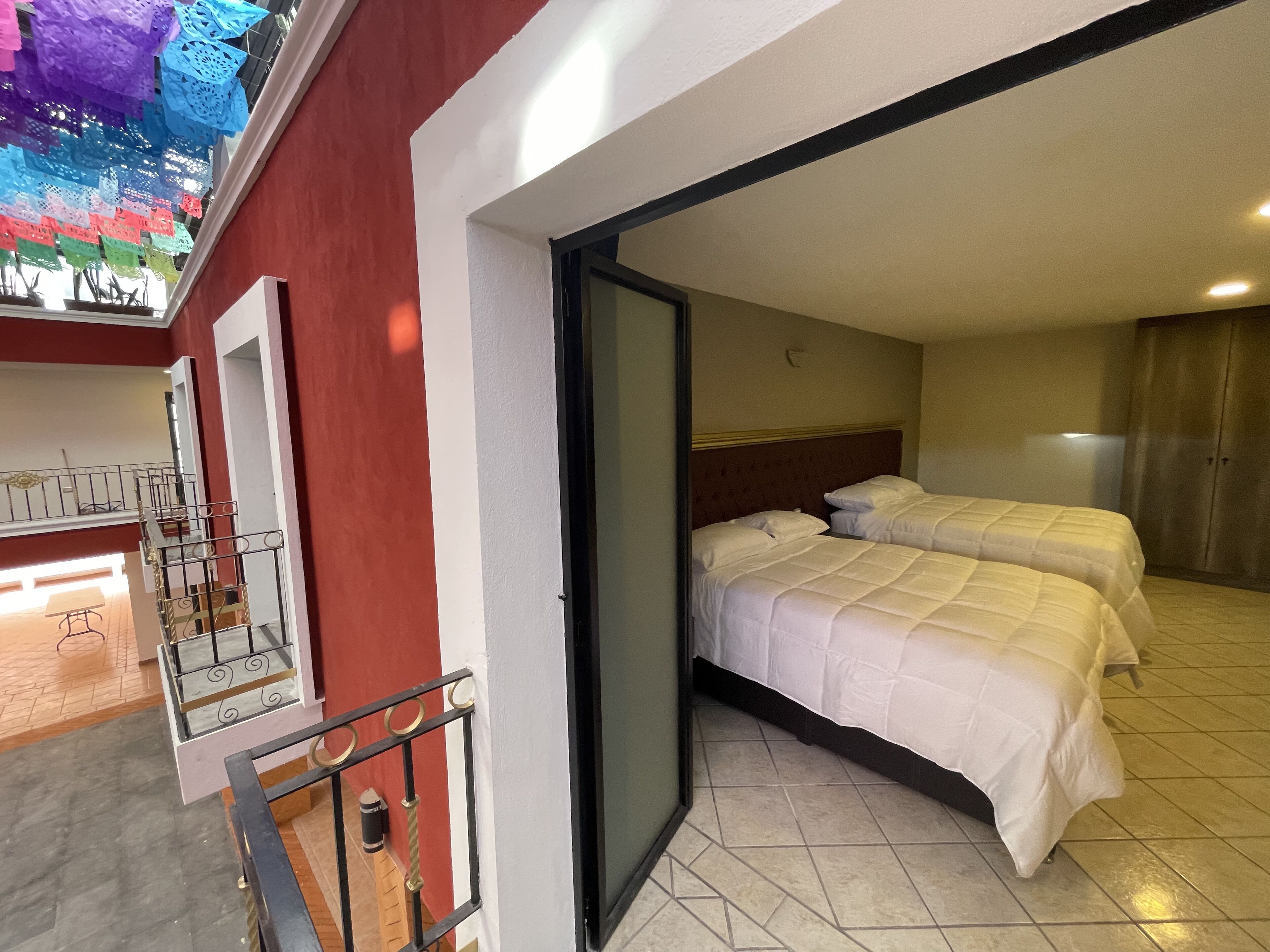 Une chambre d’hôtel avec deux lits, un balcon avec une rambarde et une vue sur l’extérieur.