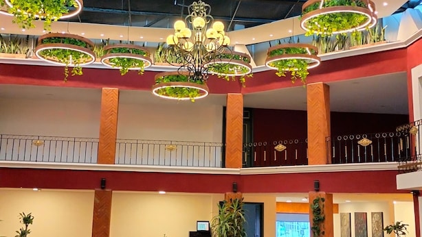 A spacious indoor area with multiple dining tables and chairs, a chandelier, and circular ceiling decorations with greenery. - Hotel Casa Real  (San Andrés Cholula)