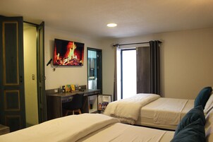 Habitación de hotel con dos camas, un escritorio con silla, un refrigerador y un cuadro de un incendio en la pared.