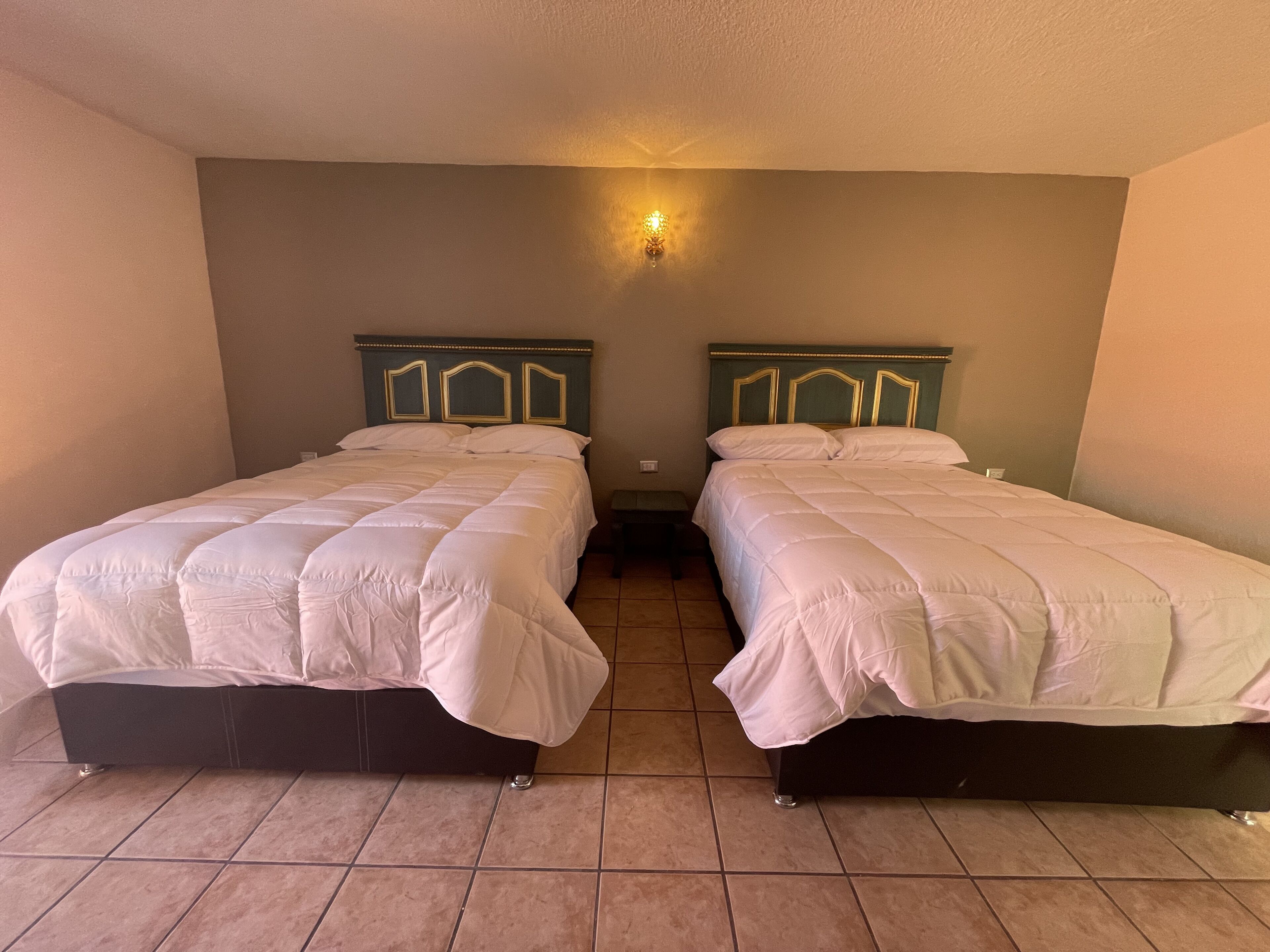 Ein Zimmer mit zwei Einzelbetten, jeweils mit Kopfteil und Nachttisch.