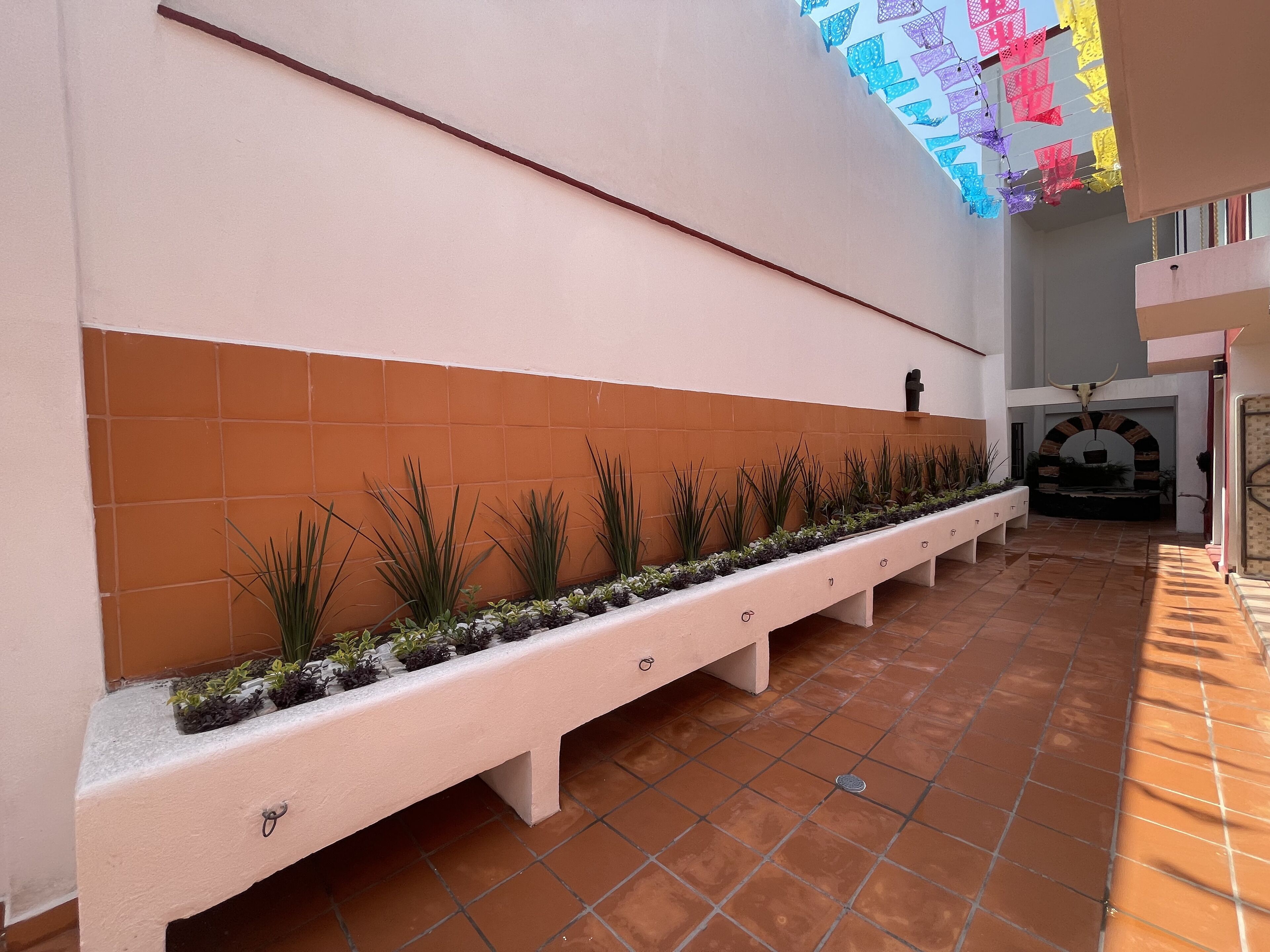 A corridor with a long bench, tiled walls, and a ceiling with colorful decorations.