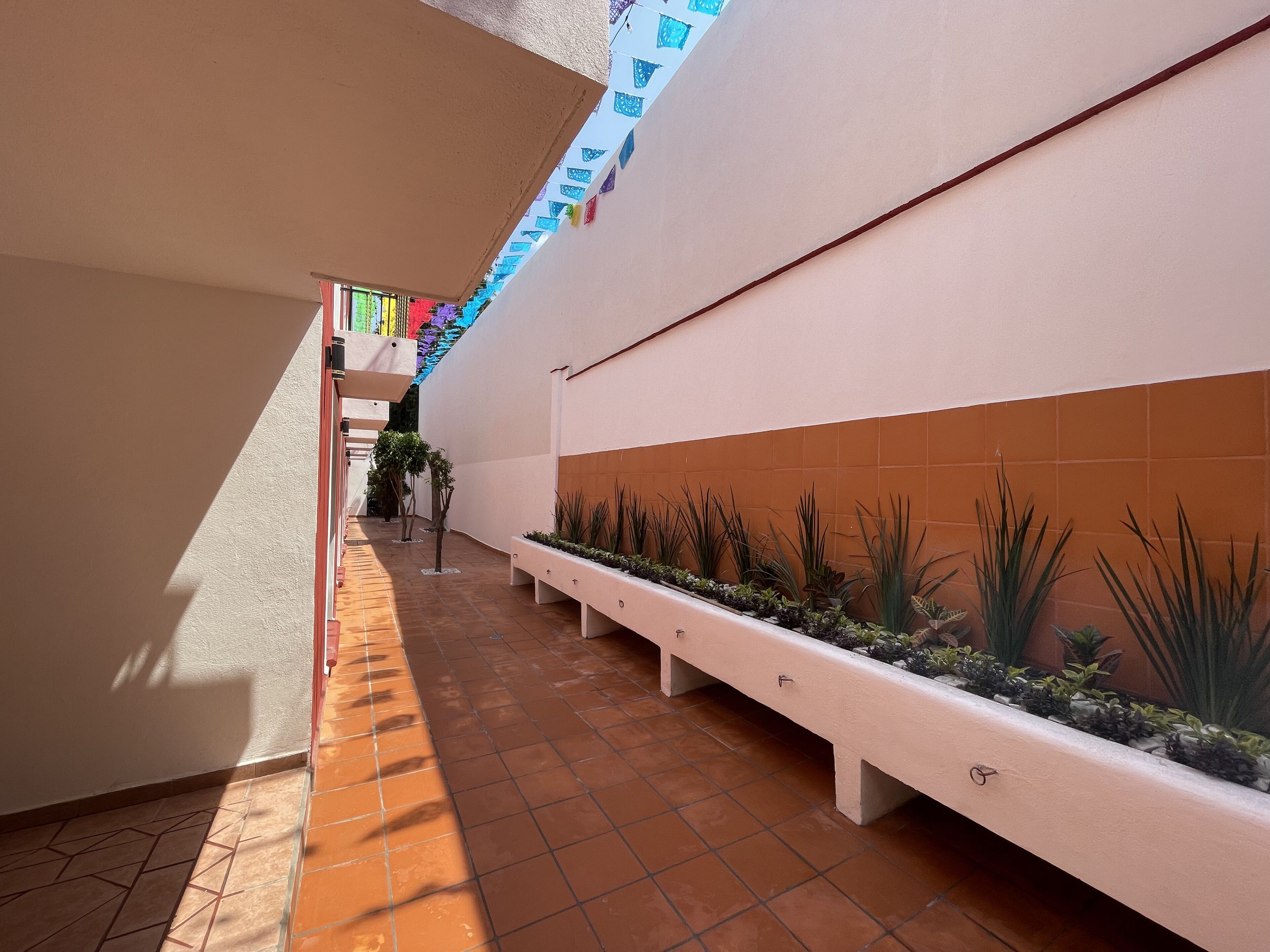 A narrow corridor with a tiled floor, a white bench, and a planter with plants.