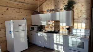 Cocina compacta con refrigerador, microondas, lavamanos y estufa.