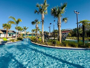 A swimming pool with palm trees and a building in the background.