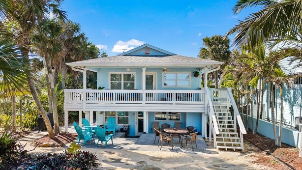 A two-story house with a balcony, outdoor seating, and a staircase.
