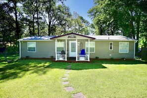 A single-story mobile home with a porch, a welcome sign, and a small front yard. - FLAT lake lot: water toys: Clemson ->17 miles (Fair Play)