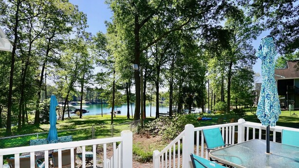 A deck with outdoor furniture overlooking a lake with boats, surrounded by trees.