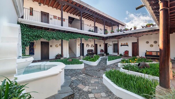 A courtyard with a stone pathway, white planters, and a pool. - Casita La Pila (Antigua Guatemala)