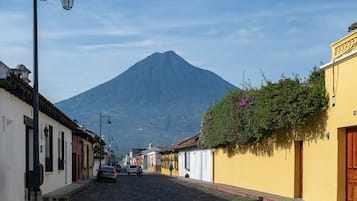A cobblestone street with buildings on either side, a mountain in the background, and a street lamp.