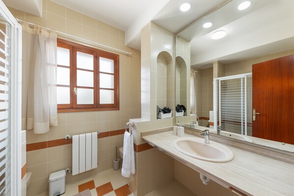 A modern bathroom with a large mirror, a sink, and a toilet.