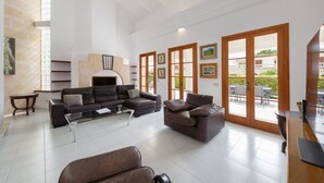 Ein geräumiges Wohnzimmer mit einer Eckcouch, einem Kamin und Blick auf die Terrasse durch große Schiebetüren.
