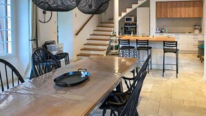 Una cocina moderna con una mesa de comedor de madera, sillas negras y una isla de cocina con taburetes de bar.