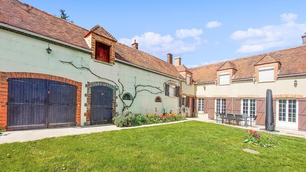 Un patio con césped verde, una estatua y un edificio de techos de teja y paredes de ladrillo.