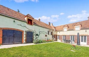 A courtyard with a green lawn, a statue, and a building with a tiled roof and brick walls. - Amazing home in Flacy with WiFi (Flacy)