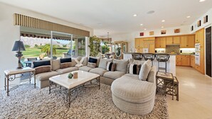 Ein großzügiges Wohnzimmer mit einer großen Eckcouch, einem Couchtisch und Blick auf die Küche.