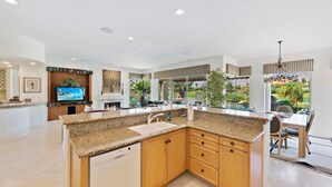 Eine moderne Küche mit Granit-Arbeitsplatten, Holzschränken, einem integrierten Geschirrspüler und einer großen Kochinsel.