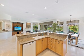 A modern kitchen with granite countertops, wooden cabinets, a built-in dishwasher, and a large island.