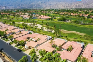 Un quartiere residenziale con case, un campo da golf e montagne sullo sfondo.