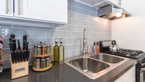 A modern kitchen with stainless steel appliances, a double sink, and a knife block. - 5-10 minute walk to the beach.   (Long Beach)