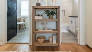 A hallway with a wooden console table holding decorative items, a dining area with a table and chairs, and a bathroom with a bathtub and toilet visible. - 5-10 minute walk to the beach.   (Long Beach)
