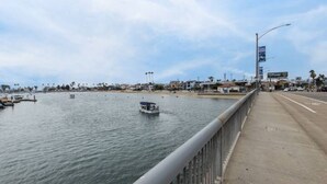A waterfront view with a bridge, boats, and a beach in the background. - 5-10 minute walk to the beach.   (Long Beach)