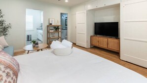 A bedroom with a bed, a TV, a ceiling fan, a small table with a plant, and a wardrobe. - 5-10 minute walk to the beach.   (Long Beach)