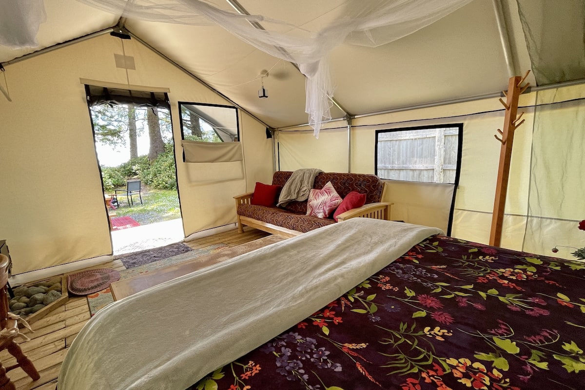 Una habitación con carpa, una cama, un sofá y una ventana.